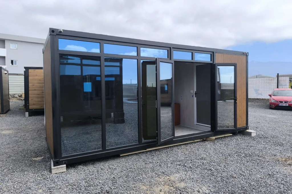 Construcción modular de estructura negra y grandes ventanales al aire libre